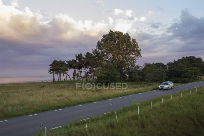 Car driving along road under overcast sky in Sweden — Stock Photo