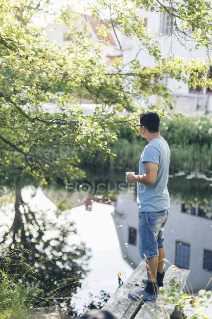 Hombre adulto de pie junto al río en Mortfors, Suecia - foto de stock