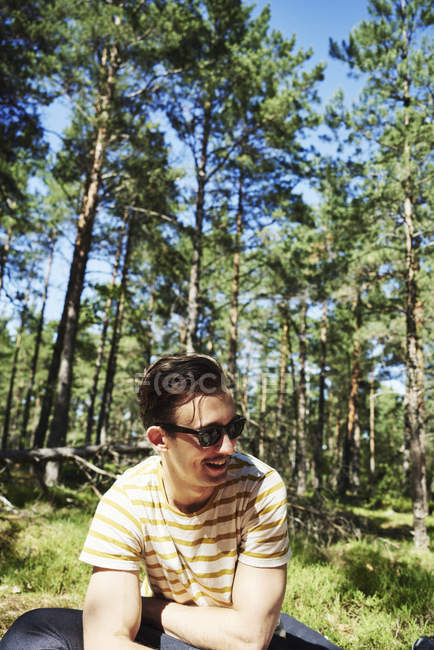 Молодий чоловік сидить у лісі, зосереджується на передньому плані — стокове фото
