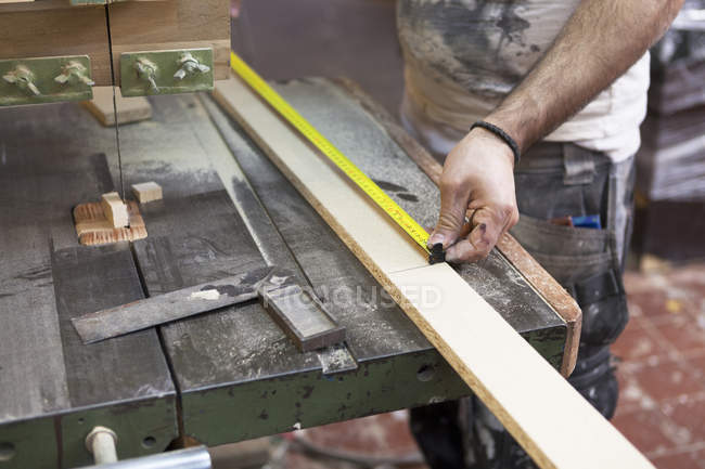 Cropped view of carpenter measuring length of wood — Stock Photo