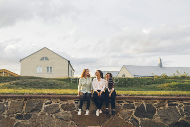 Три молодые женщины, сидящие на стене в шведском городе Скрона — стоковое фото