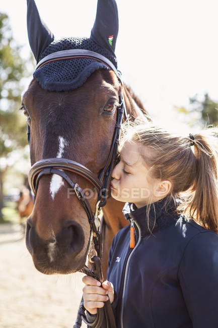 Teenage girl kissing horse, focus on foreground — Stock Photo