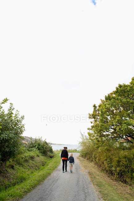 Mãe e filho caminhando na estrada rural — Fotografia de Stock