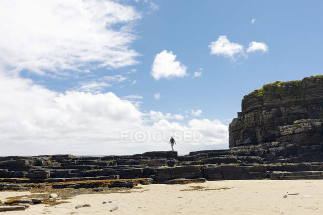 Mulher andando em rochas de praia na Escócia — Fotografia de Stock