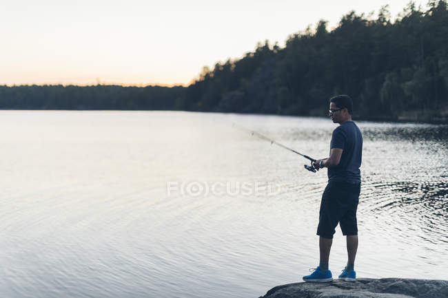 Риболовля людини на озері, фокус на передньому плані — стокове фото
