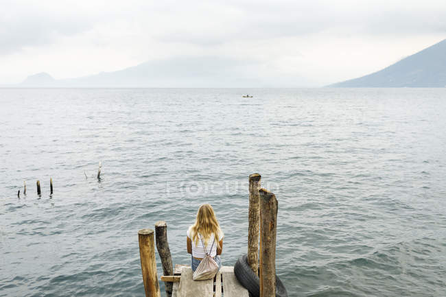 Rear view of woman sitting on pier, selective focus — Stock Photo