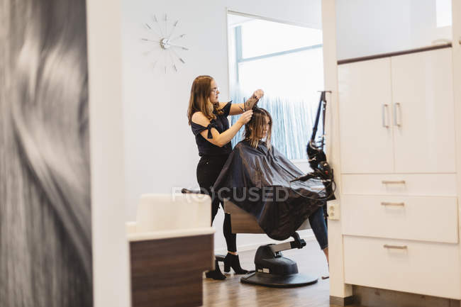 Hairdresser cutting clients hair in salon, selective focus — Stock Photo