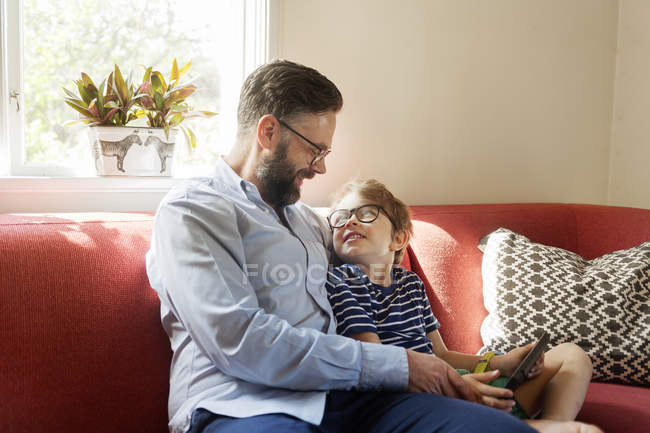 Отец и мальчик с помощью устройства в гостиной — стоковое фото