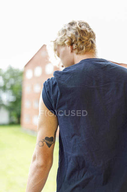 Vue arrière du jeune homme avec tatouage sur le bras, mise au premier plan — Photo de stock
