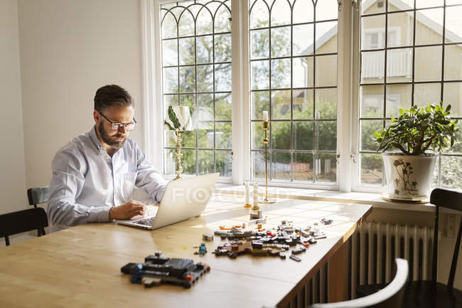 Средний взрослый мужчина с ноутбуком в столовой, избирательный фокус — стоковое фото