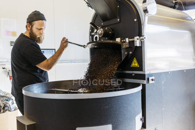 Hombre usando máquina de tostado de café, enfoque selectivo - foto de stock