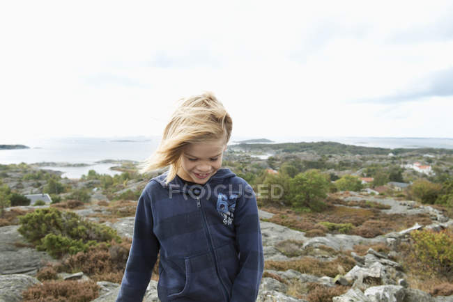 Joyeux garçon debout sur des rochers au bord de la mer, se concentrer sur le premier plan — Photo de stock
