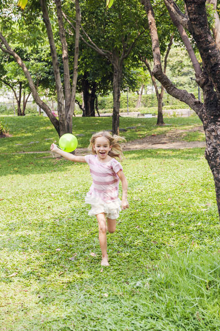Girl running with balloon in park, focus on foreground — Stock Photo