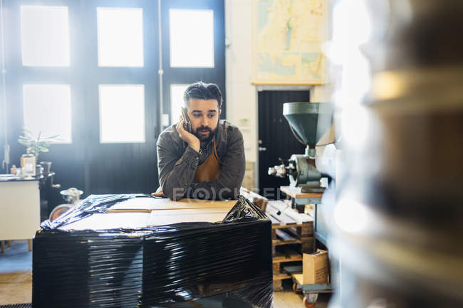 Small business owner at coffee roaster shop talking on cell phone — Stock Photo
