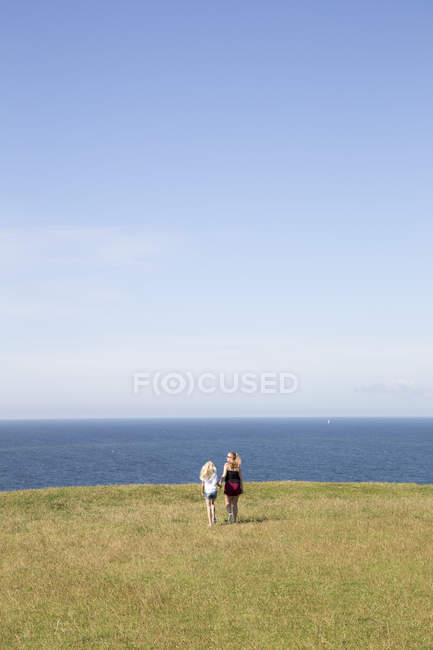 Sisters walking in field next to sea in Kaseberga, Sweden — Stock Photo