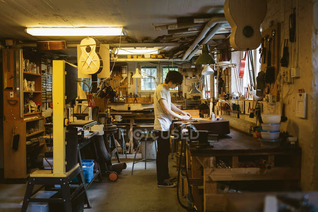 Ремесленник, работающий в мастерской по изготовлению гитары — стоковое фото