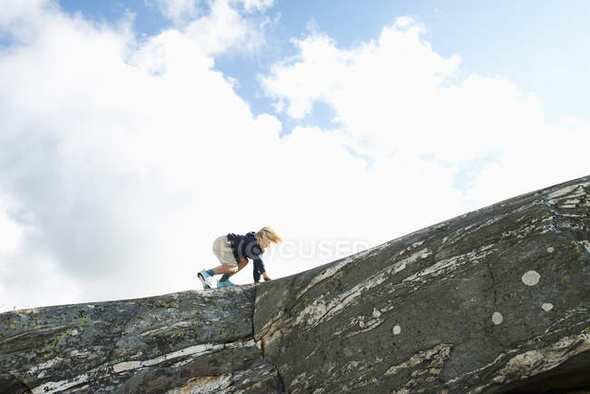 Visão de baixo ângulo de menino escalando na parede de rocha — Fotografia de Stock
