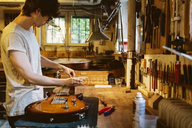Artesano trabajando en taller de fabricación de guitarras, enfoque selectivo - foto de stock