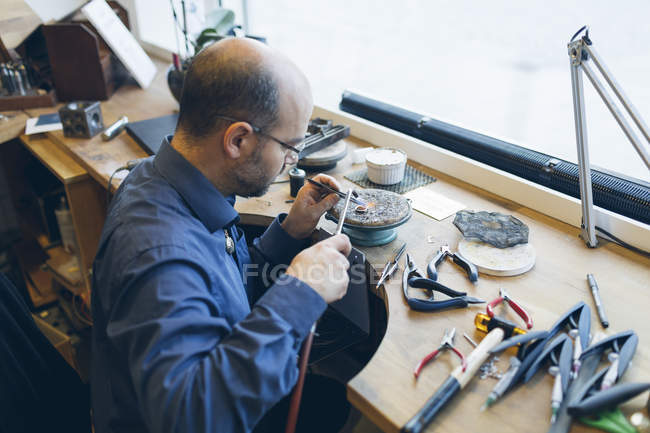 Orfèvre travaillant avec chalumeau à l'atelier, mise au point sélective — Photo de stock