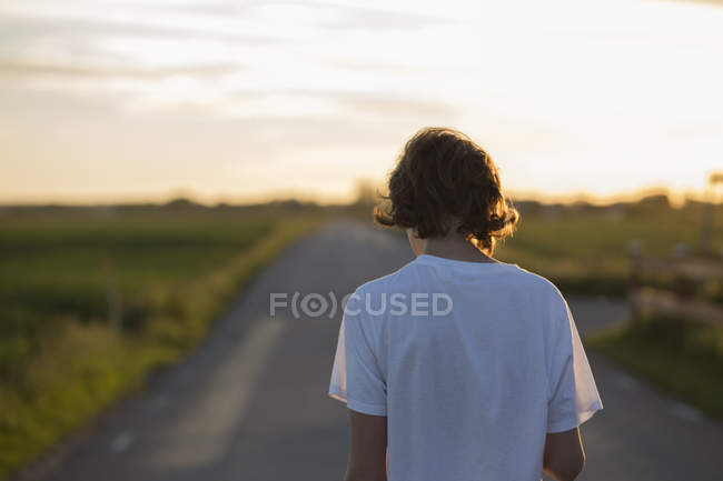 Teenage boy outdoors at sunset, focus on foreground — Stock Photo