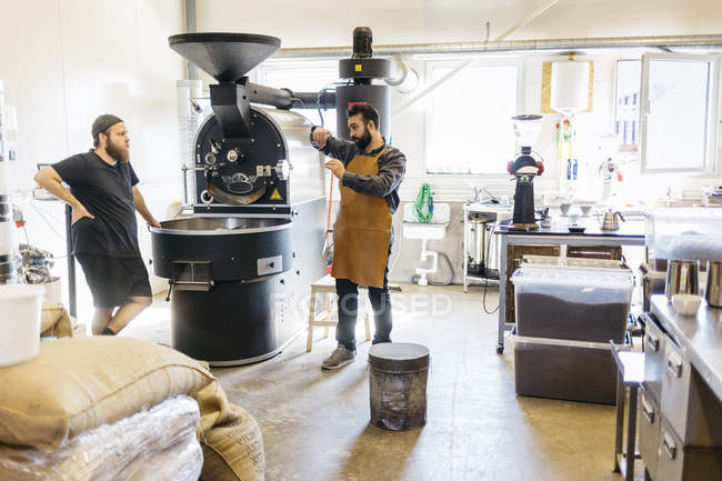 Dois homens conversando contra máquina de torrefação de café — Fotografia de Stock
