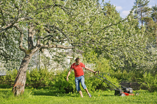Homme mi-adulte tondre la pelouse à Heinola, Finlande — Photo de stock