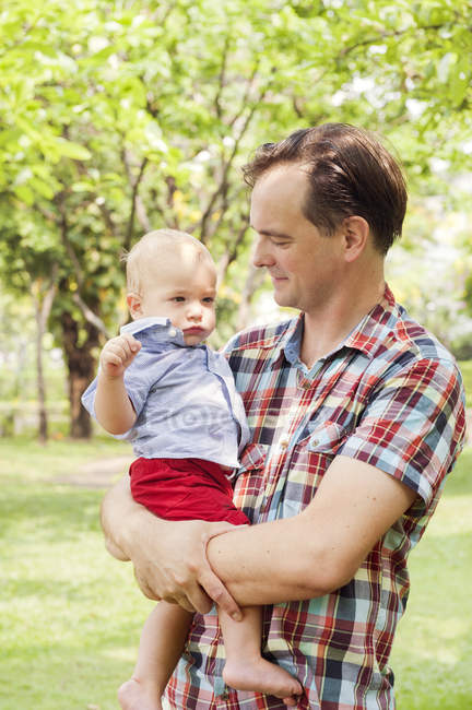 Батько, що носить сина в парку, зосередитися на передньому плані — стокове фото