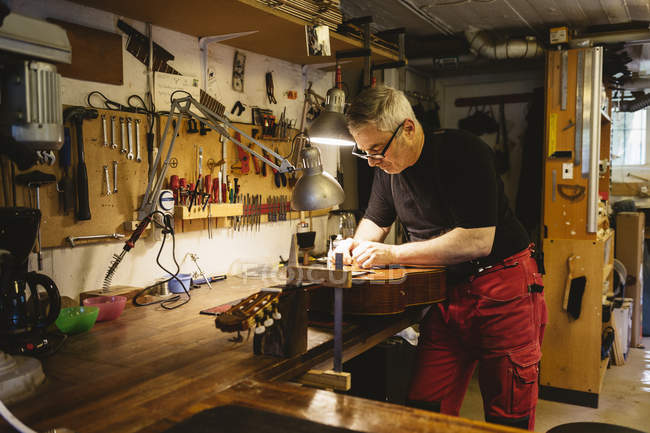 Ремесленник, работающий в мастерской по изготовлению гитары — стоковое фото