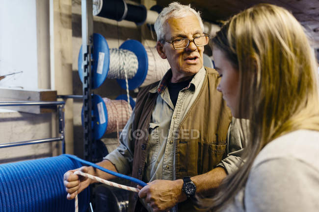 Fabricante de cordas conversando com aprendiz na loja, foco seletivo — Fotografia de Stock