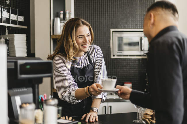 Barista che serve una tazza di caffè al cliente nel caffè — Foto stock