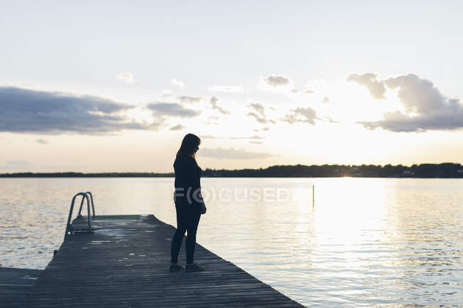 Жінка середнього віку, що стоїть на пірсі, вибірковий фокус — стокове фото