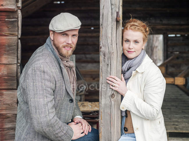 Jeune couple assis à l'extérieur de la cabane en rondins, mise au premier plan — Photo de stock
