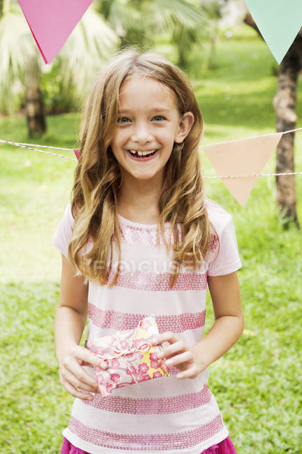 Portrait of girl holding gift at birthday party in park — Stock Photo