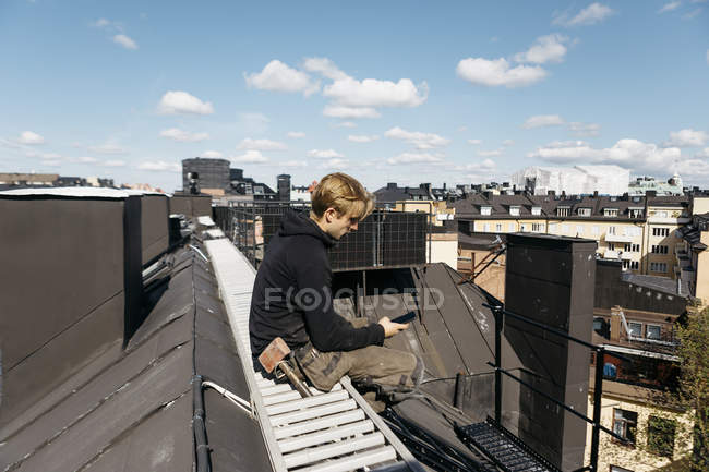 Dachdecker mit Smartphone in der Arbeitspause in Stockholm, Schweden — Stockfoto