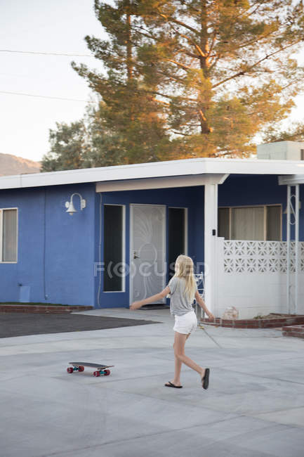 Fille marche à skateboard par maison, foyer sélectif — Photo de stock