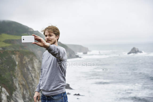 Homem tomando selfie no Big Sur na Califórnia, EUA, foco seletivo — Fotografia de Stock