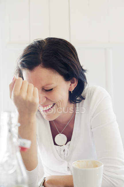 Femme adulte moyenne riant avec tasse à café, mise au point sélective — Photo de stock