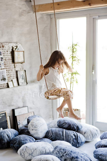 Menina balançando no balanço interior, foco em primeiro plano — Fotografia de Stock