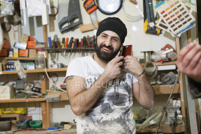 Carpenter talking on cell phone, focus on foreground — Stock Photo
