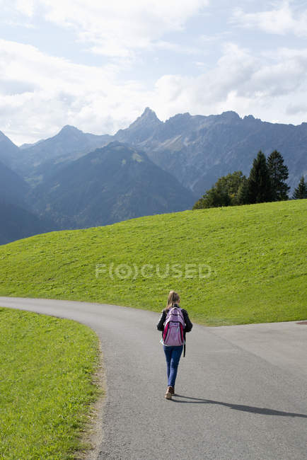 Visão traseira da menina andando ao longo da estrada rural em Vorarlberg, Áustria — Fotografia de Stock