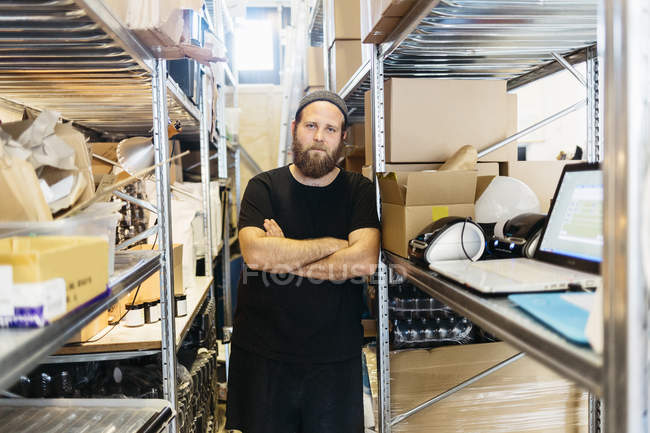 Coffee roaster posing between shelves, focus on foreground — Stock Photo
