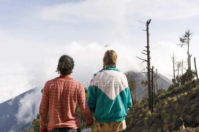 Vista trasera de pareja cogida de la mano en la montaña en Guatemala - foto de stock