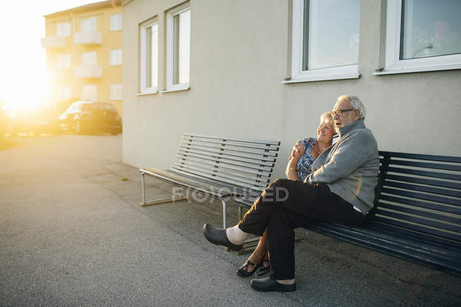 Seniorenpaar umarmt sich auf Bank, Fokus auf Vordergrund — Stockfoto