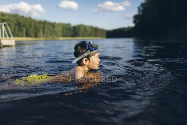 Vista lateral del niño nadando en el lago en Kappemalagol, Suecia - foto de stock