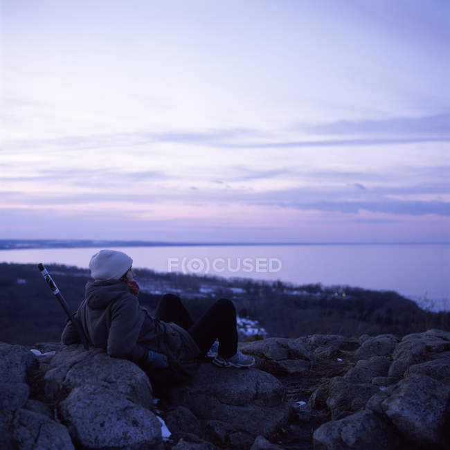 Жінка сидить на камені і дивиться в море — стокове фото