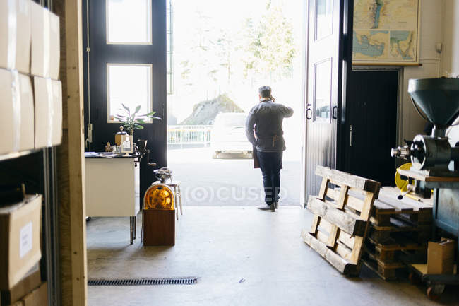 Rear view of coffee roaster talking on cell phone — Stock Photo