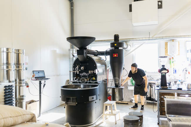 Homme utilisant une machine de torréfaction de café, mise au point sélective — Photo de stock