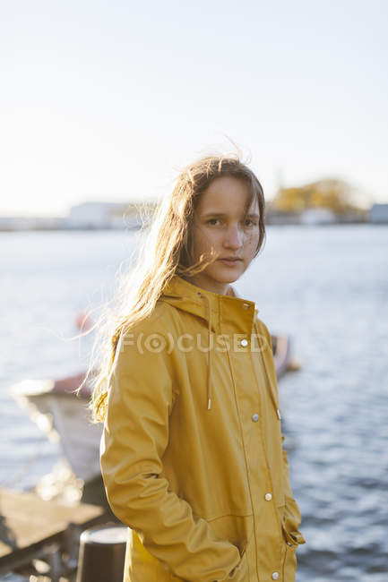 Chica vistiendo impermeable amarillo por mar - foto de stock