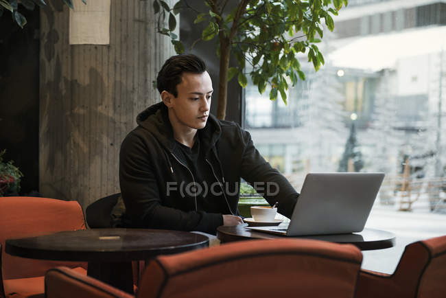 Молодий чоловік сидить у кафе, вибірковий фокус — стокове фото