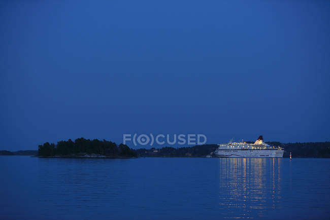 Ferry de passageiros iluminado à noite, refletindo em água — Fotografia de Stock